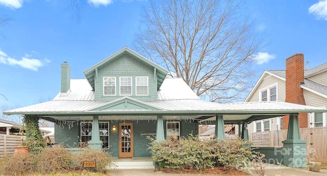 view of front of home with a chimney, covered porch, and metal roof