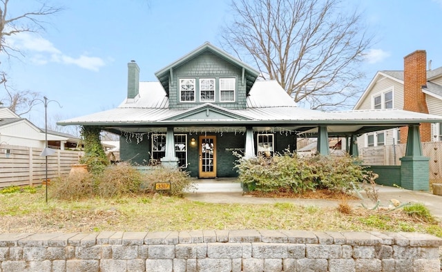 view of front of property featuring a chimney, metal roof, and fence