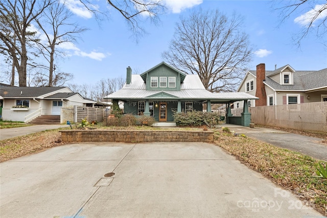 bungalow with a chimney, a porch, metal roof, and fence