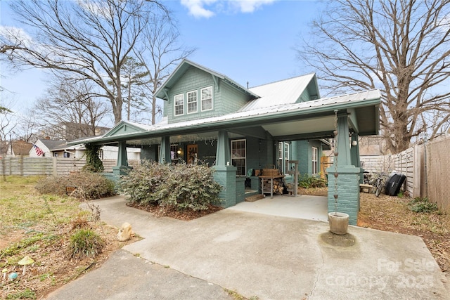 view of front of house with an attached carport, fence, a porch, concrete driveway, and metal roof