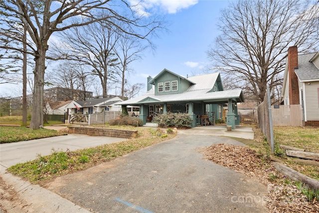 bungalow-style house featuring aphalt driveway, a porch, a carport, and fence