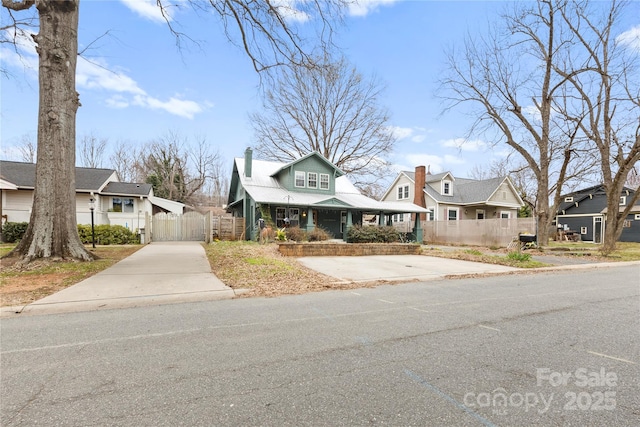 view of front of home featuring fence, covered porch, a residential view, and a chimney