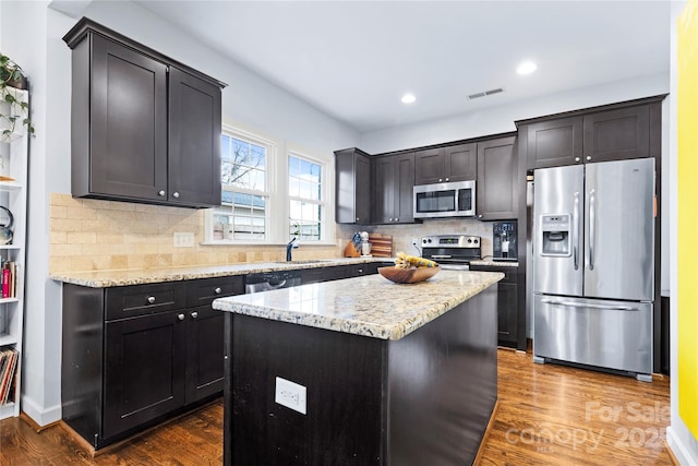 kitchen with visible vents, a sink, stainless steel appliances, light stone countertops, and dark wood-style flooring