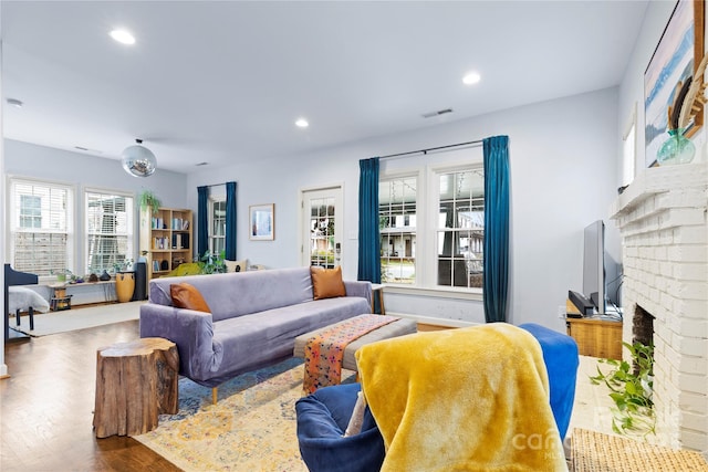 living room featuring wood finished floors, a brick fireplace, recessed lighting, and visible vents