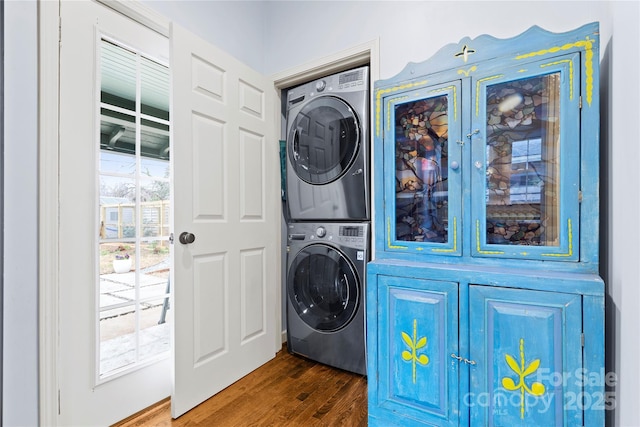 washroom with stacked washer and dryer, wood finished floors, and laundry area