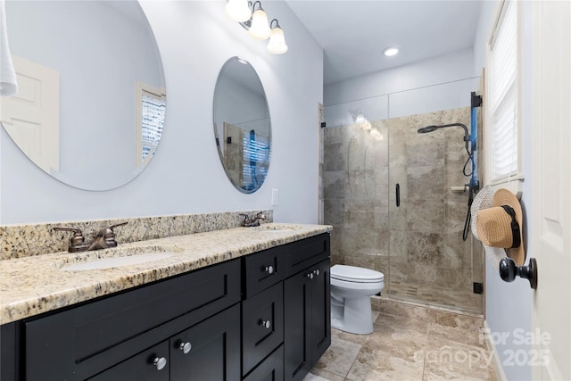 full bathroom featuring double vanity, toilet, a stall shower, and a sink