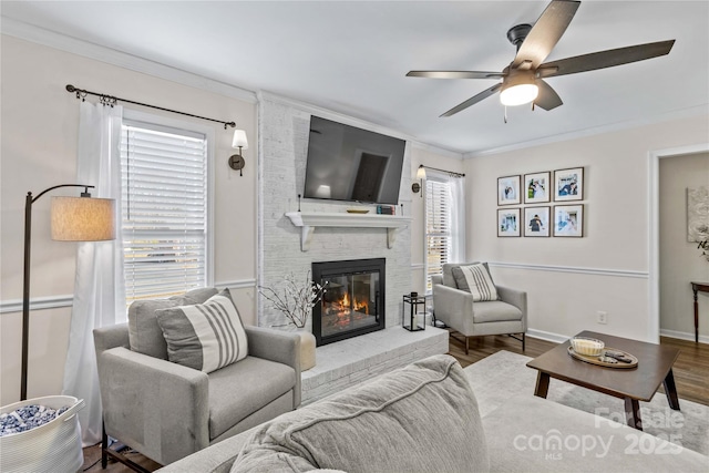 living room with hardwood / wood-style floors, a brick fireplace, ceiling fan, and crown molding