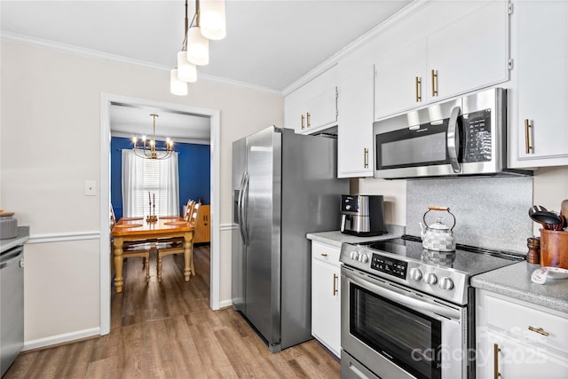 kitchen with decorative light fixtures, ornamental molding, a notable chandelier, white cabinetry, and stainless steel appliances