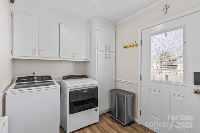 clothes washing area featuring washer and clothes dryer, cabinets, light wood-type flooring, and crown molding