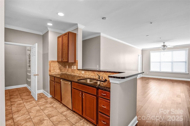 kitchen with sink, dark stone countertops, kitchen peninsula, stainless steel dishwasher, and crown molding