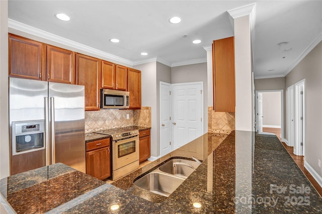 kitchen with appliances with stainless steel finishes, dark stone counters, and sink