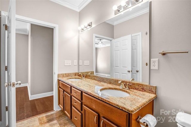 bathroom with hardwood / wood-style floors, toilet, vanity, ornamental molding, and ceiling fan