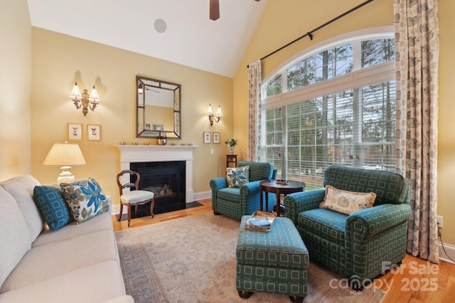 living room featuring hardwood / wood-style flooring, ceiling fan, and vaulted ceiling