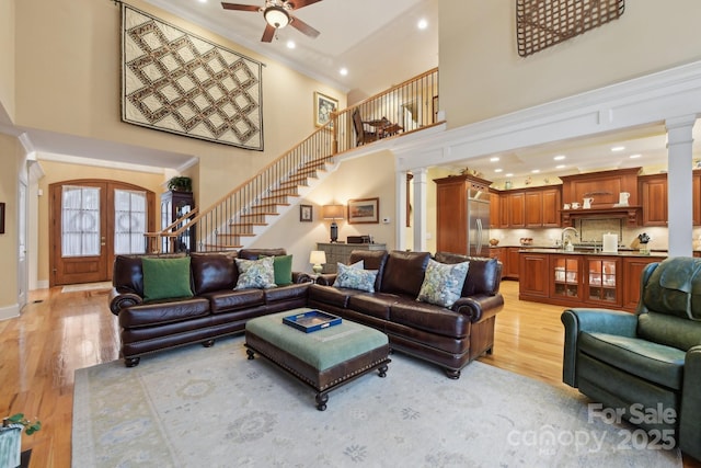 living room with french doors, sink, ceiling fan, ornate columns, and light hardwood / wood-style floors