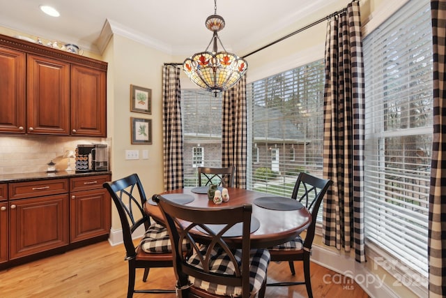 dining area featuring a healthy amount of sunlight, ornamental molding, light wood-type flooring, and an inviting chandelier