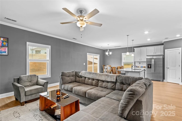 living room featuring ceiling fan, light hardwood / wood-style flooring, a healthy amount of sunlight, and ornamental molding