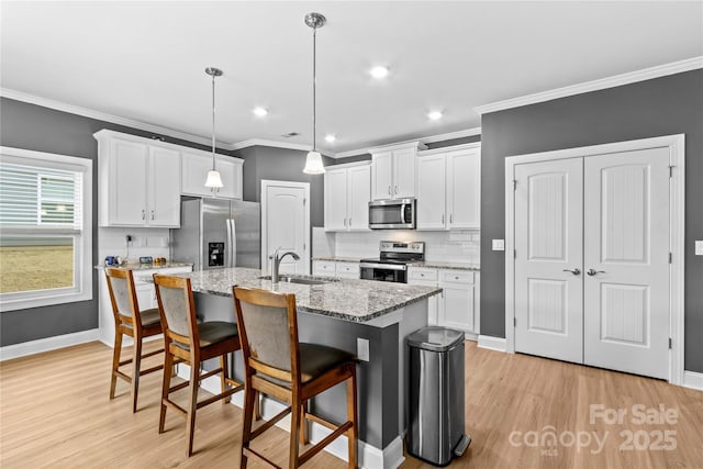 kitchen featuring white cabinets, pendant lighting, an island with sink, and stainless steel appliances