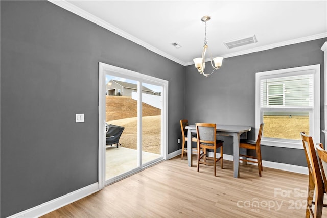 dining room featuring crown molding, light hardwood / wood-style floors, and an inviting chandelier