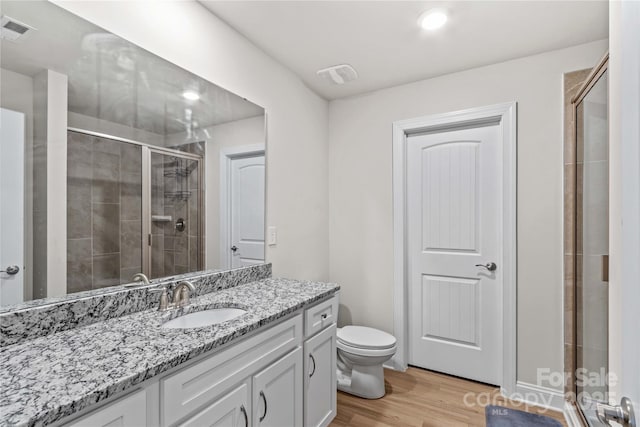 bathroom with a shower with shower door, toilet, wood-type flooring, and vanity