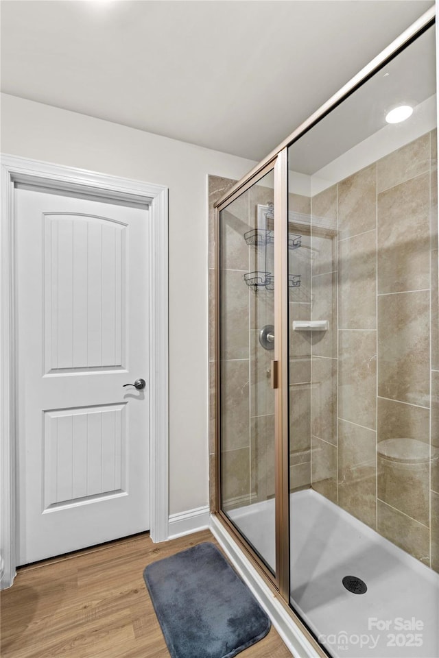 bathroom with a shower with door and hardwood / wood-style flooring