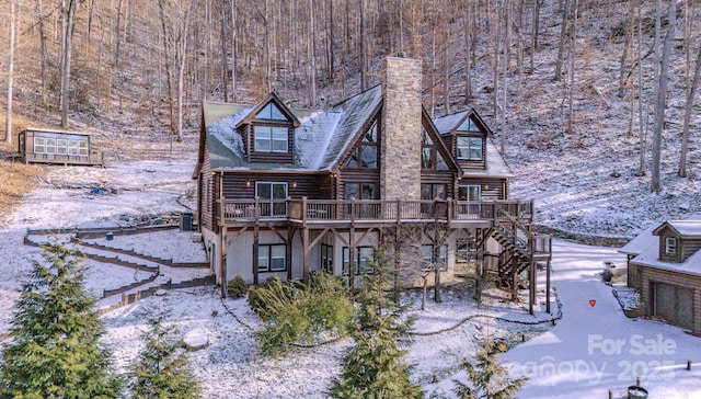 snow covered house featuring a wooden deck