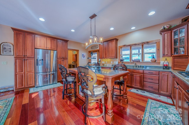 kitchen with light wood-type flooring, stainless steel appliances, sink, and decorative light fixtures