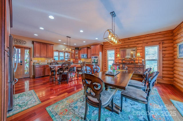 dining room with dark hardwood / wood-style floors, rustic walls, and french doors