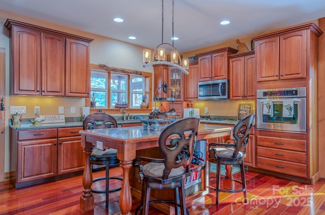 kitchen with a breakfast bar area, stainless steel appliances, hardwood / wood-style floors, and a kitchen island