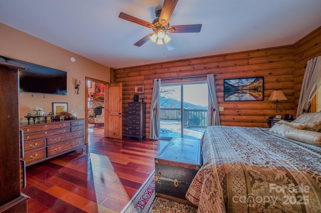 bedroom with rustic walls, dark hardwood / wood-style flooring, access to outside, and ceiling fan