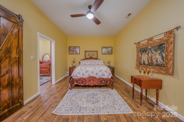 bedroom featuring ceiling fan and a barn door