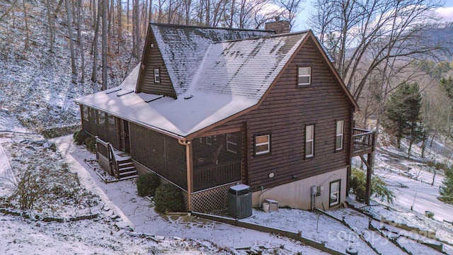 view of snow covered exterior featuring central AC unit and a sunroom