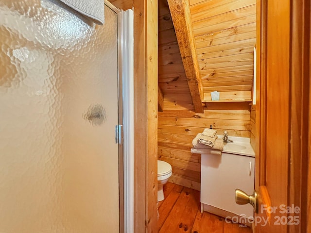 bathroom with toilet, hardwood / wood-style floors, an enclosed shower, vanity, and wood walls