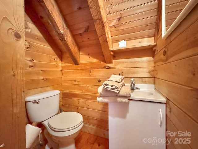 bathroom featuring vanity, toilet, wood walls, wooden ceiling, and beam ceiling