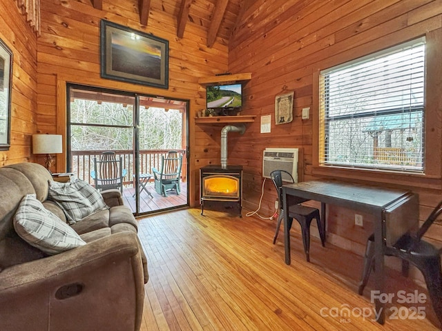 living room with wooden ceiling, plenty of natural light, vaulted ceiling with beams, and a wood stove