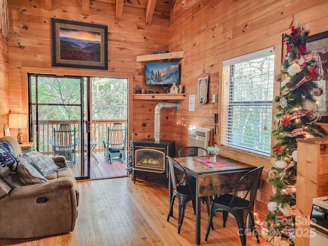 dining room with light hardwood / wood-style floors, wooden walls, beamed ceiling, and an AC wall unit