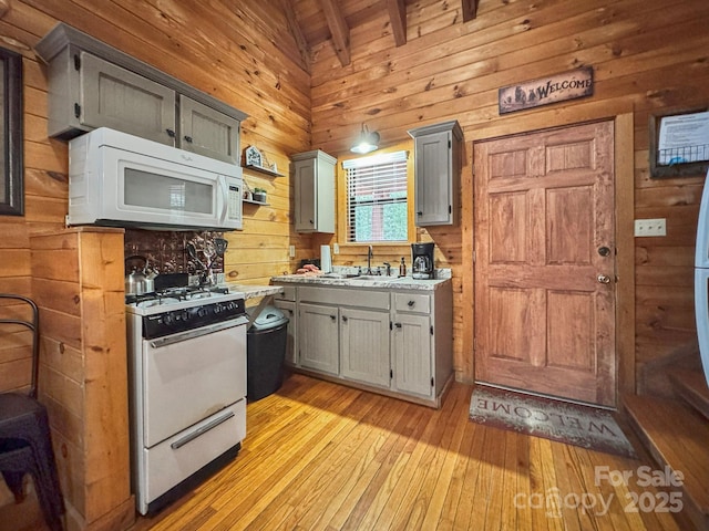 kitchen with white appliances, light hardwood / wood-style flooring, gray cabinets, and lofted ceiling with beams