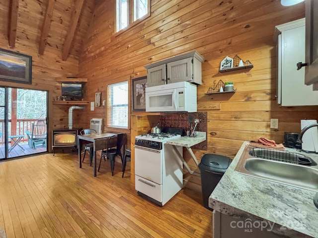 kitchen featuring white appliances, wood ceiling, sink, a wood stove, and beam ceiling