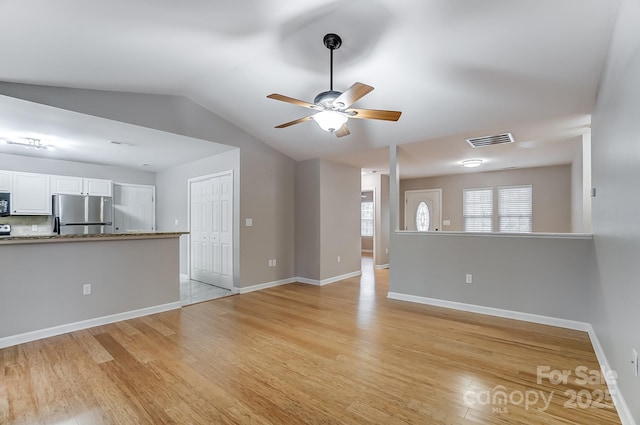 unfurnished living room featuring ceiling fan, vaulted ceiling, and light hardwood / wood-style flooring