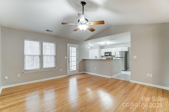 unfurnished living room with light wood-type flooring, vaulted ceiling, ceiling fan, and sink