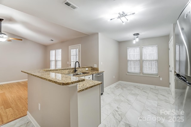 kitchen with light stone countertops, sink, ceiling fan, kitchen peninsula, and appliances with stainless steel finishes