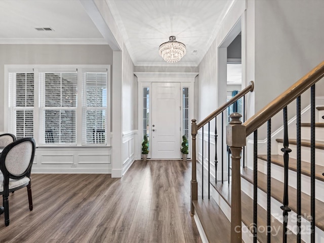 foyer entrance featuring hardwood / wood-style flooring, crown molding, and an inviting chandelier