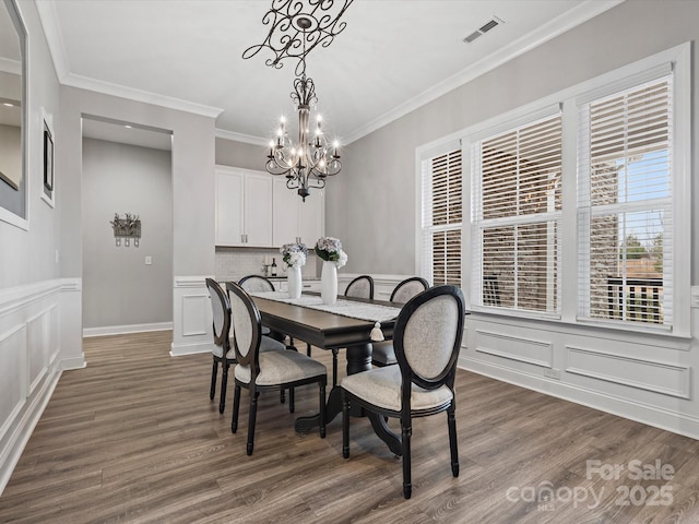 dining space with crown molding, dark hardwood / wood-style floors, and a notable chandelier