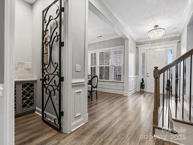 foyer featuring a notable chandelier, ornamental molding, and dark hardwood / wood-style floors