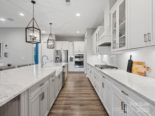 kitchen with appliances with stainless steel finishes, white cabinets, decorative backsplash, hanging light fixtures, and light stone countertops