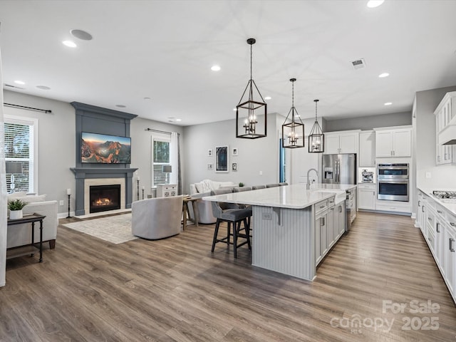 kitchen featuring pendant lighting, white cabinets, a kitchen breakfast bar, stainless steel appliances, and a spacious island