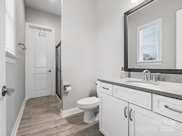 bathroom with vanity, wood-type flooring, a shower with shower door, and toilet