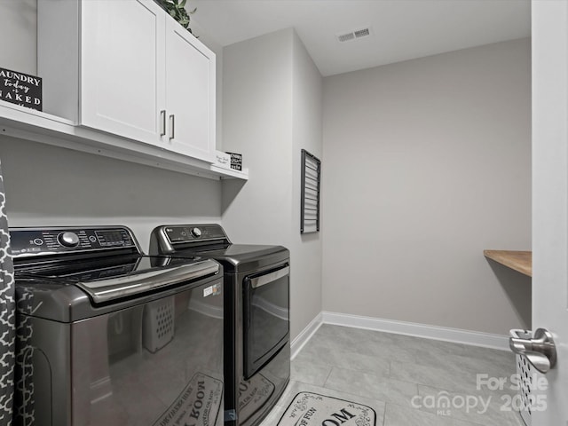 clothes washing area featuring cabinets, washing machine and dryer, and light tile patterned flooring