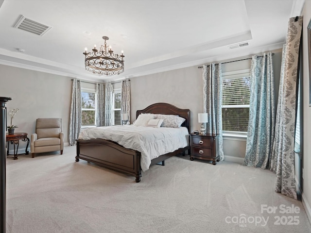 carpeted bedroom featuring an inviting chandelier and a tray ceiling