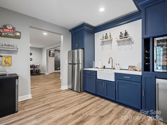 kitchen featuring stainless steel refrigerator, sink, wine cooler, light hardwood / wood-style floors, and blue cabinetry