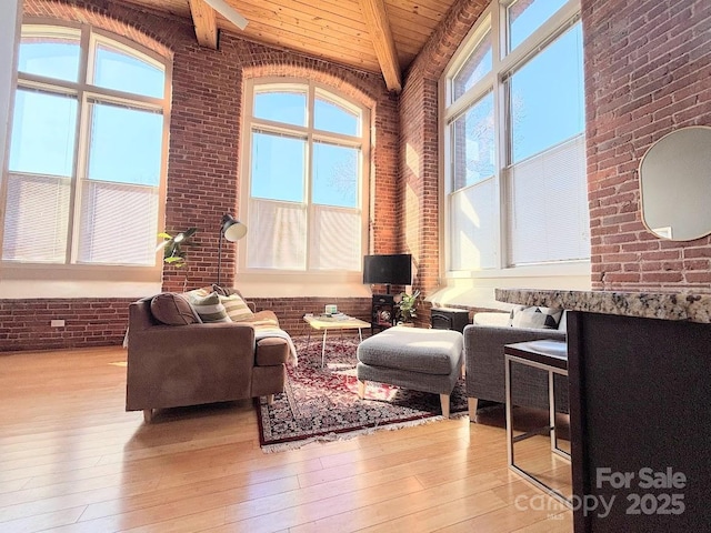 interior space with beamed ceiling, brick wall, a healthy amount of sunlight, and wood ceiling